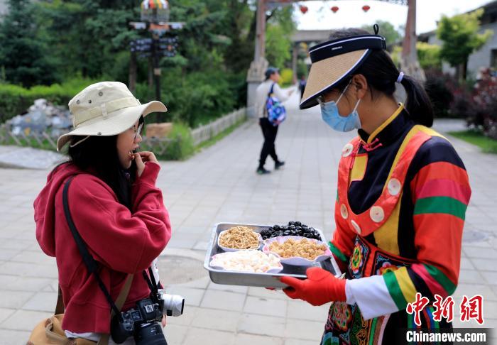 圖為身穿土族服飾的女性介紹當(dāng)?shù)靥厣〕??！⊙Φ?攝